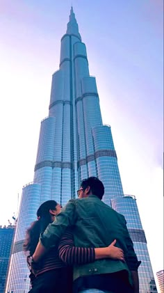 two people are hugging in front of the burj building, with skyscrapers behind them