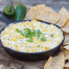 a bowl of corn dip surrounded by tortilla chips