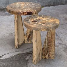 two wooden stools sitting next to each other on the cement floor in front of a building