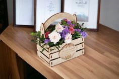 a wooden box filled with flowers sitting on top of a table next to two framed pictures