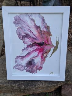 a painting of a leaf on display in a white frame with green and purple leaves