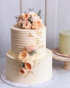 a three tiered cake with flowers on the top and bottom, sitting on a table