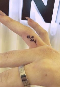 two people with matching tattoos on their fingers, one holding the other's hand