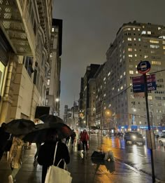 people walking down the street with umbrellas on a rainy night