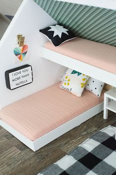 a doll house with a bed and desk in the corner next to it on top of a wooden floor