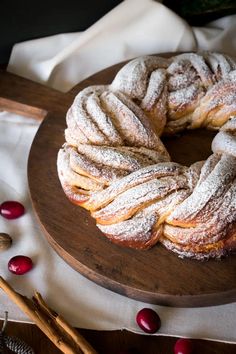 powdered sugar covered pastry sitting on top of a wooden platter next to cranberries