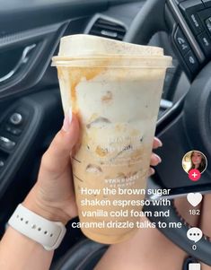 a woman holding up a drink in her car