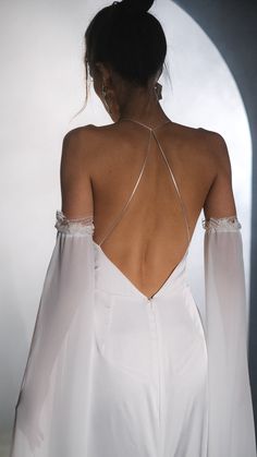 the back of a woman's white dress with long sleeves and an open shoulder