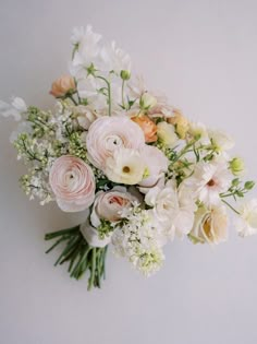 a bunch of flowers that are sitting on a table in front of a white wall