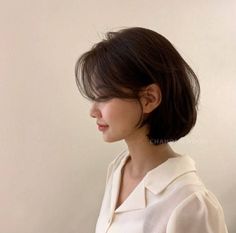 a woman with short hair wearing a white shirt and looking off to the side in profile