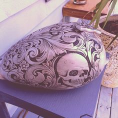 a skull shaped vase sitting on top of a wooden table next to a potted plant