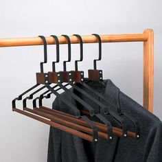 a coat rack with clothes hanging on it's sides and four wooden hangers