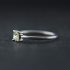 an engagement ring with a square cut diamond in the center on a black table top