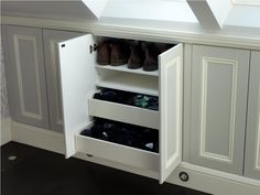 an open cabinet with several pairs of shoes on it in a room that has white walls