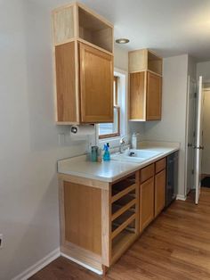 an empty kitchen with wooden cabinets and white counter tops on hard wood flooring in the foreground