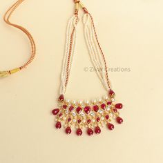 This unique Tanmani features 7 white-colored stones, complemented by pearls woven into the necklace strings. Red drop shape beads add a charming touch, enhancing the beauty of this exquisite design. Inspired by the Peshwa style, this necklace is a popular choice among women in Maharashtra. Crafted with 3mm pearls strings intricately woven and decorated with Jeri, the necklace comes with an adjustable thread. Please note that this is our handmade creation. You may also consider pairing it with ou Affordable Necklace For Puja And Diwali, Festive Adjustable White Necklace, Red Temple Jewelry Pearl Necklace For Festivals, Red Pearl Temple Jewelry Necklace For Festivals, Red Pearl Necklace Temple Jewelry For Festivals, Traditional Adjustable White Kundan Necklace, Traditional Red Beaded Pearl Necklace, Festive Red Pearl Jewelry, Adjustable Red Pearl Necklace