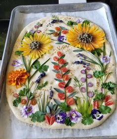 an uncooked pizza with flowers and herbs on it