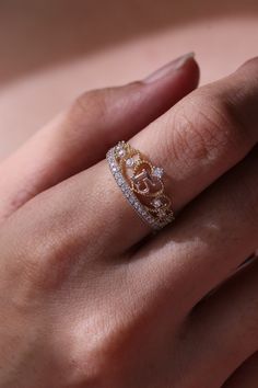 a woman's hand with a gold and diamond ring on her left hand,