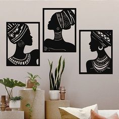 three black and white silhouettes on a wall in a living room with potted plants