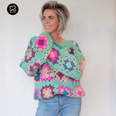 a woman wearing a colorful crochet sweater and jeans posing for the camera with her hands on her hips