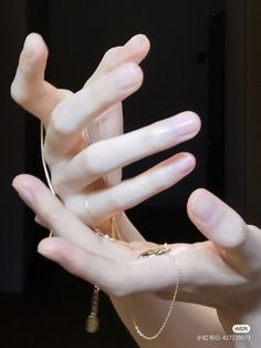 a person's hands with white manicures and gold jewelry