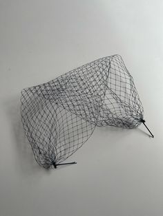 an object made out of wire sitting on top of a white table next to a wall