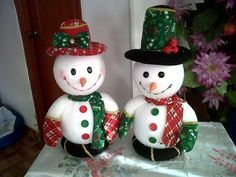 two snowmen wearing hats and scarfs on a table