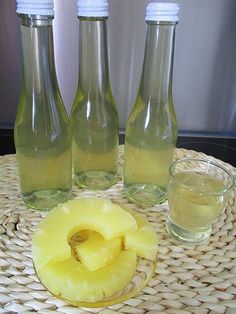 there are three bottles and two glasses on the table with pineapple slices next to them