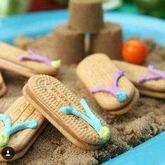 a blue plate topped with cookies covered in frosting next to an umbrella and sand