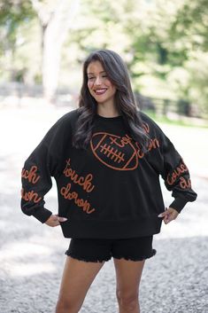 Black terry knit pullover accented with embroidered footballs and 'touchdown' In the Fall we are all Touchdown Obsessed!! Show your gameday spirit in this fabulous black sweatshirt, featuring brown embroidery braided footballs and the word 'touchdown' on the front and down the sleeves. With a crew neckline and long balloon sleeves, she's as comfy as she is festive. Tailgating never looked so stylish! True to size fit; relaxed silhouette Model is 5'5" wearing a small Fabric contains stretch Ribbe