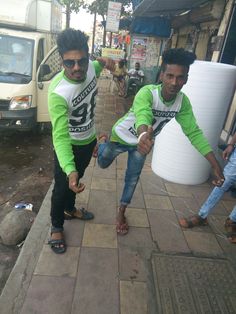 two men in green and white shirts pointing at something on the ground next to them