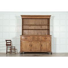 an old wooden dresser with two chairs next to it and a white brick wall in the background