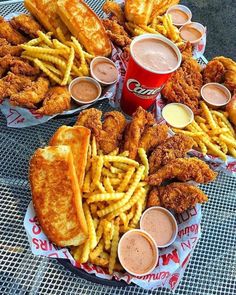 fried chicken, french fries and dips are arranged in baskets on a table top