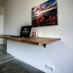 two laptops sitting on top of a wooden shelf next to a coffee cup and mug