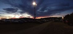 a parking lot filled with lots of parked cars under a street light at night time