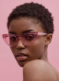 a woman wearing pink glasses against a pink background