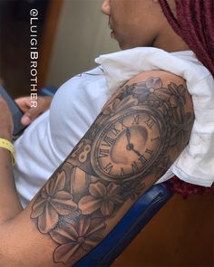 a woman with a tattoo on her arm has a clock and flowers in the background