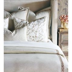 a bed with pillows on top of it next to a night stand and nightstands