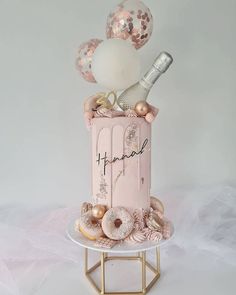 a pink birthday cake decorated with donuts and confetti on a gold stand