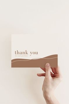 a person holding up a card with the words thank you in brown and white on it