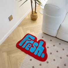 a blue and red rug on the floor next to a white couch with a potted plant