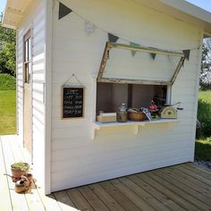 a small white building with an open window on the outside and some items in front