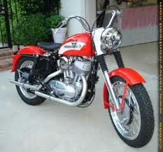 a red and white motorcycle parked in front of a building with a planter behind it