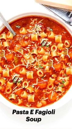 a white bowl filled with pasta and meat soup next to a slice of bread on the side