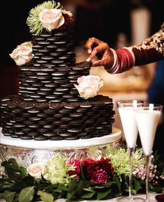 a close up of a cake on a table with flowers and glasses next to it