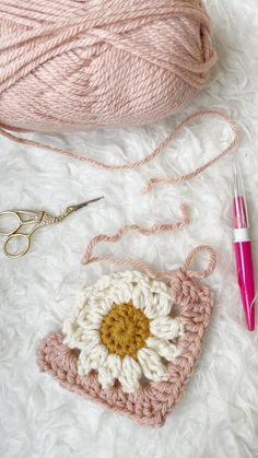 a crochet bag with a flower on it next to some yarn and scissors