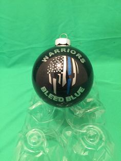 a black ornament with an american flag on it and the words warriors bleed blue