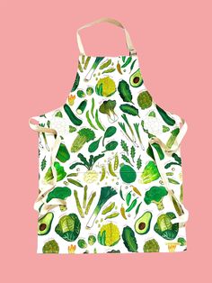 an apron with green leaves and avocados printed on it, against a pink background