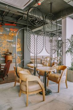 the interior of a restaurant with tables, chairs and artwork on the wall behind them