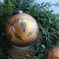 an ornament hanging from a christmas tree decorated with gold and black designs on it